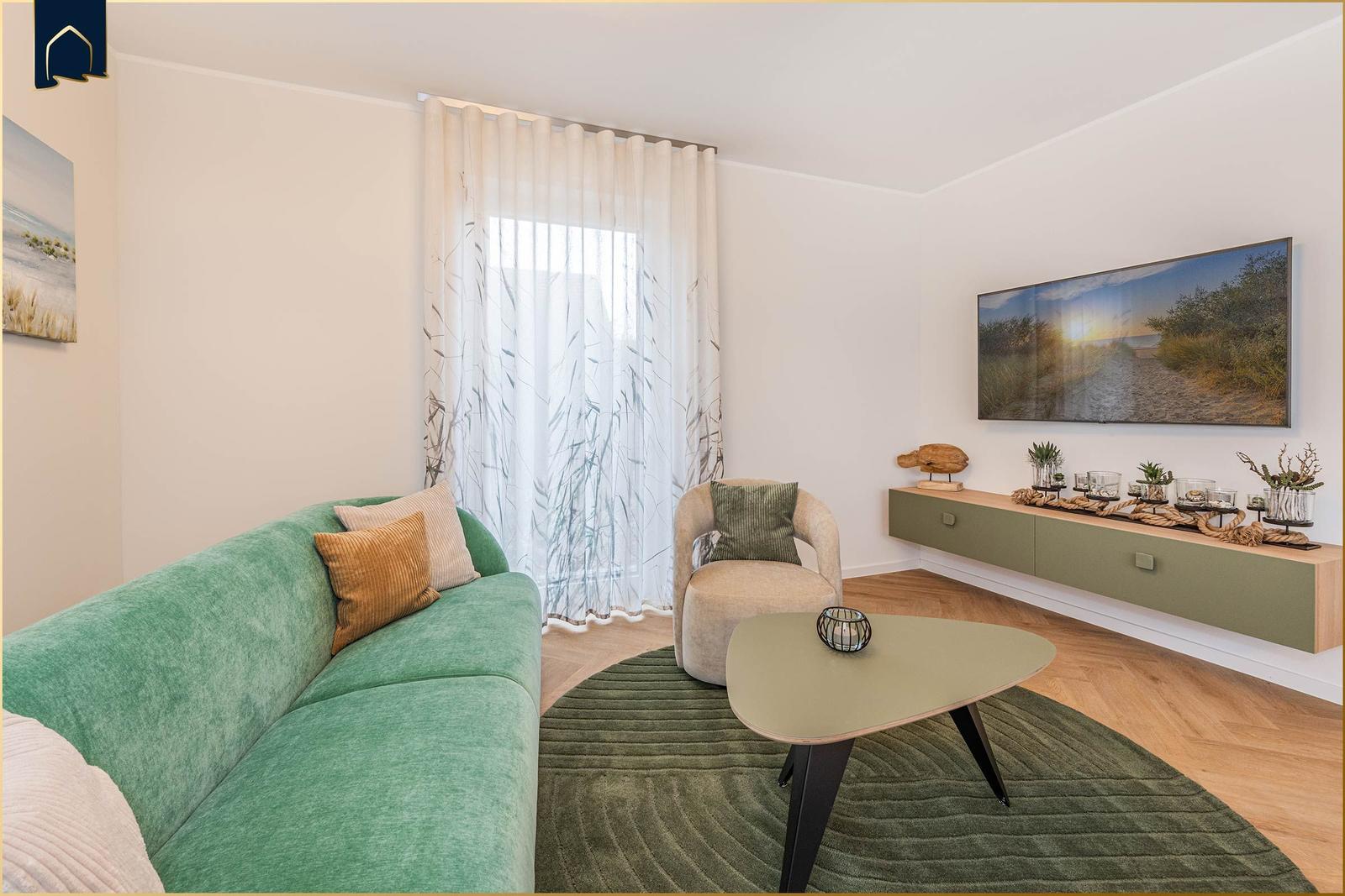 Ein Wohnzimmer mit grünem Sofa, runden Tisch und Wandbild.