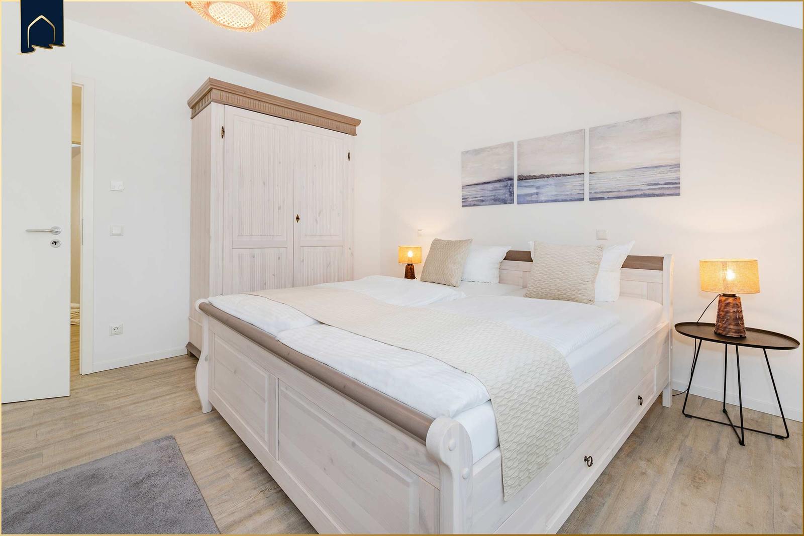 Schlafzimmer mit Doppelbett, Kleiderschrank und Nachttisch mit Lampe.