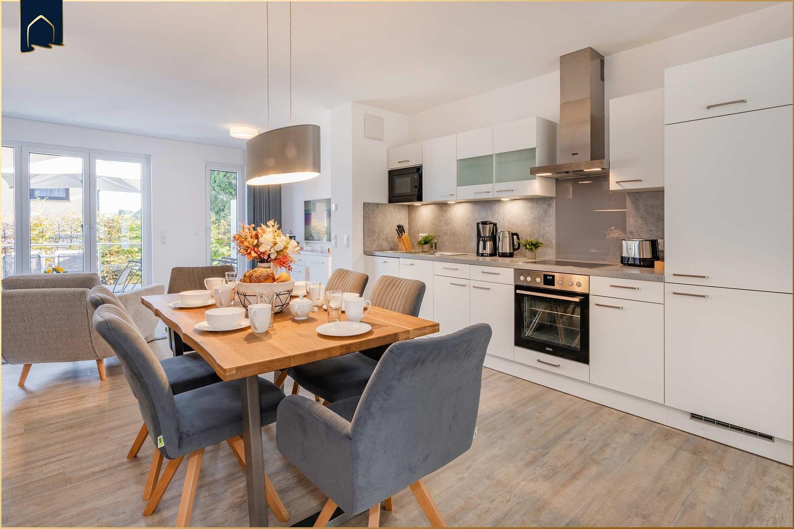 Moderne Küche mit Esstisch und Sitzgelegenheiten. Durchgang zur Terrasse.