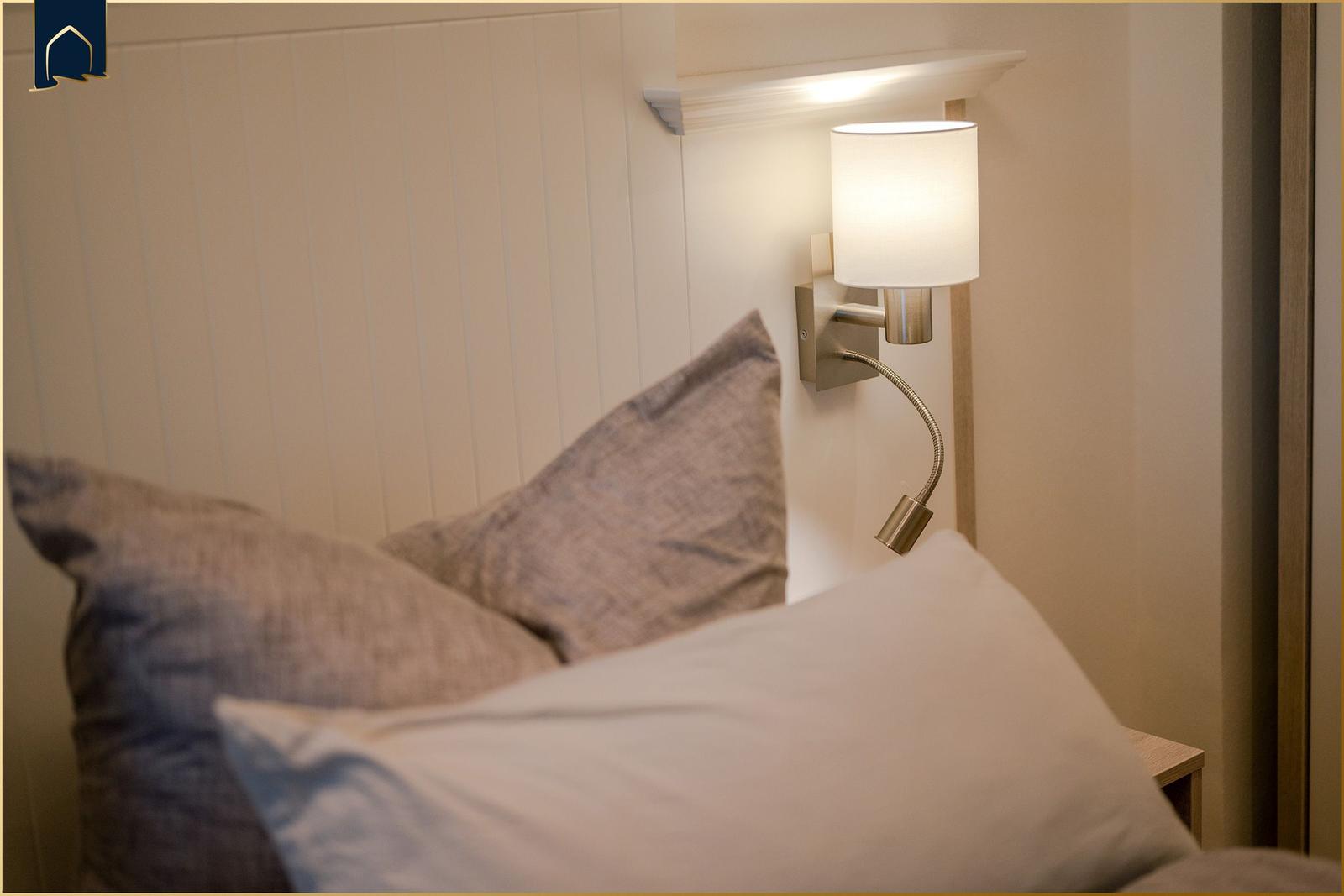 Bettkopf mit Wandlampe und Kissen