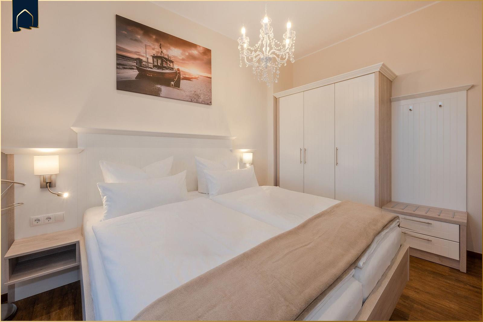 Schlafzimmer mit Doppelbett, Kleiderschrank und Deckenventilator.