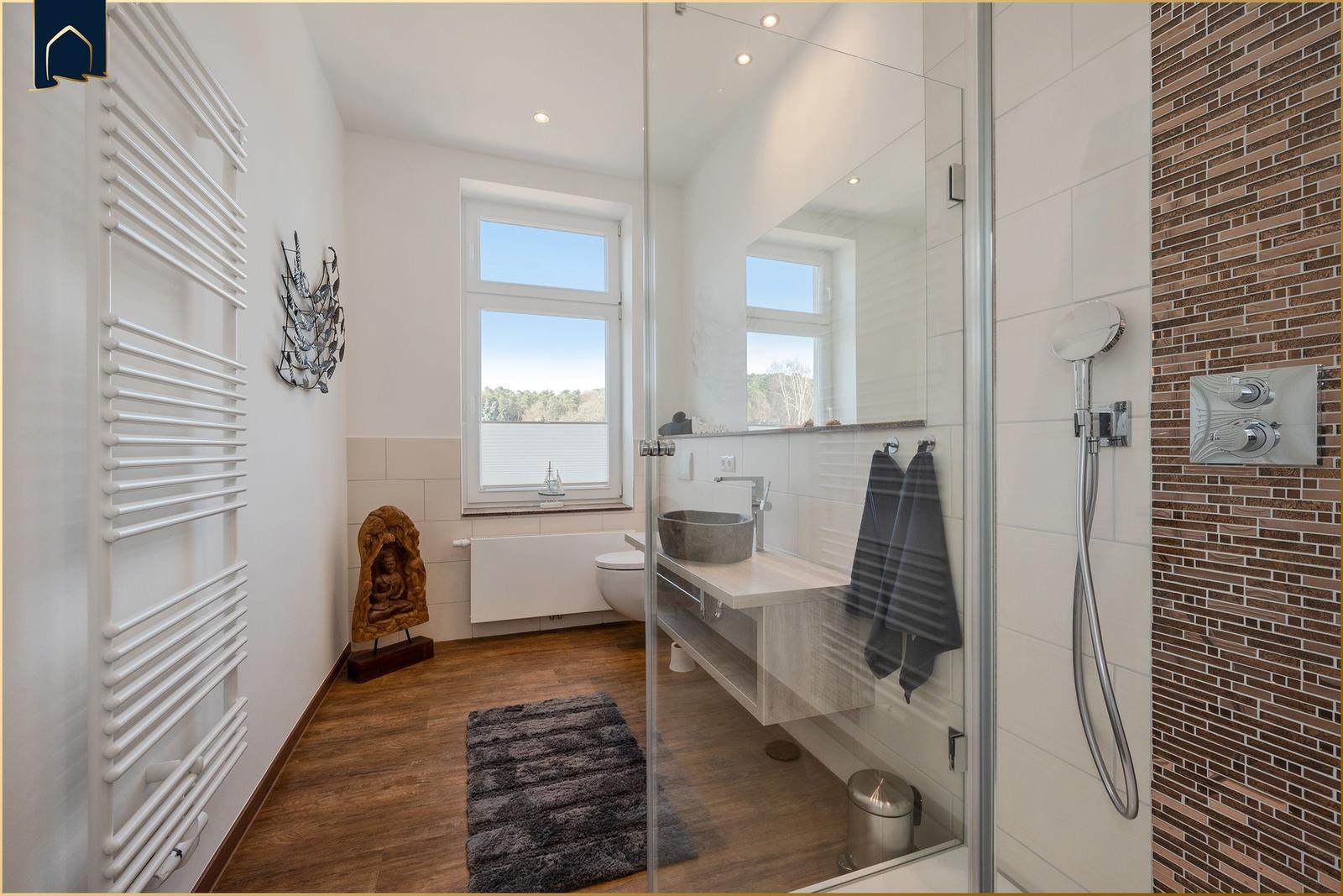 Badezimmer mit Dusche, Waschbecken und Fenster mit Blick.