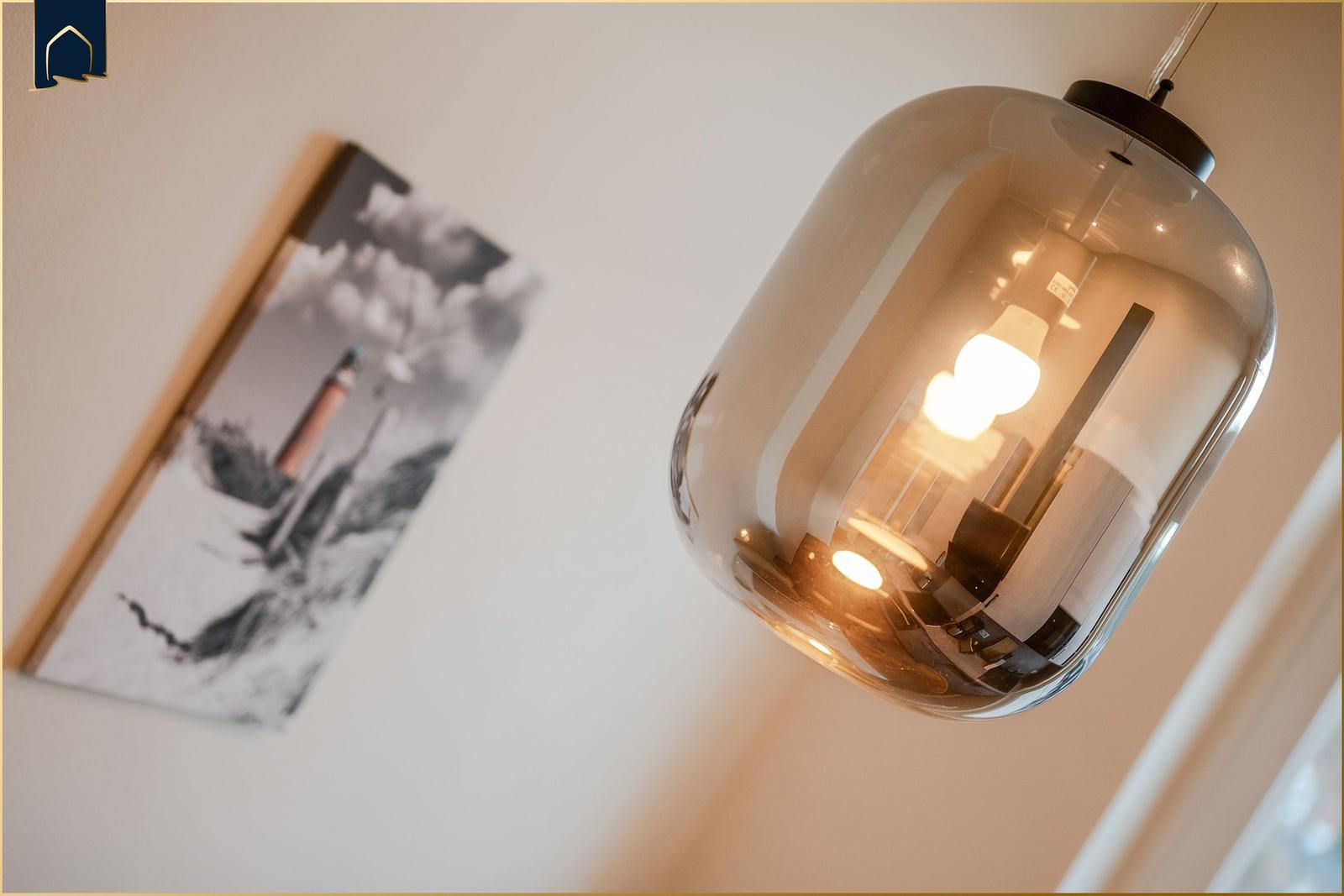 Eine hängende Lampe mit Glasgehäuse und eine Wanddekoration mit schwarz-weißem Motiv.