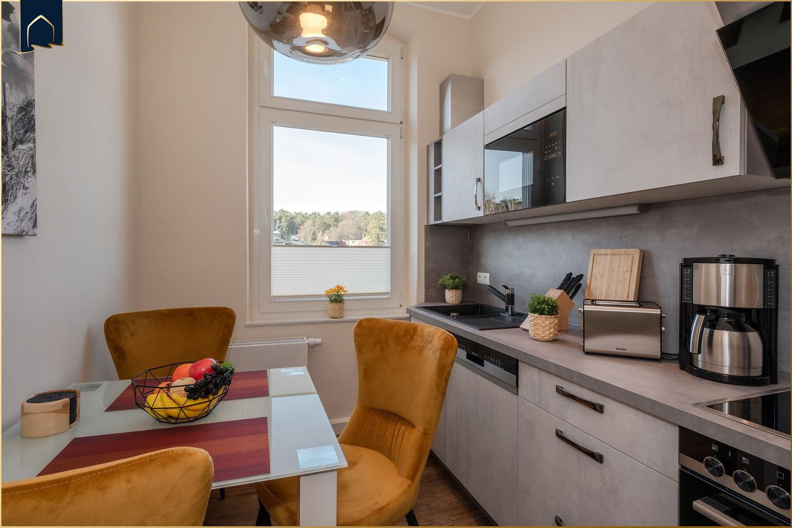 Küche mit Esstisch, Fenster und modernen Geräten.