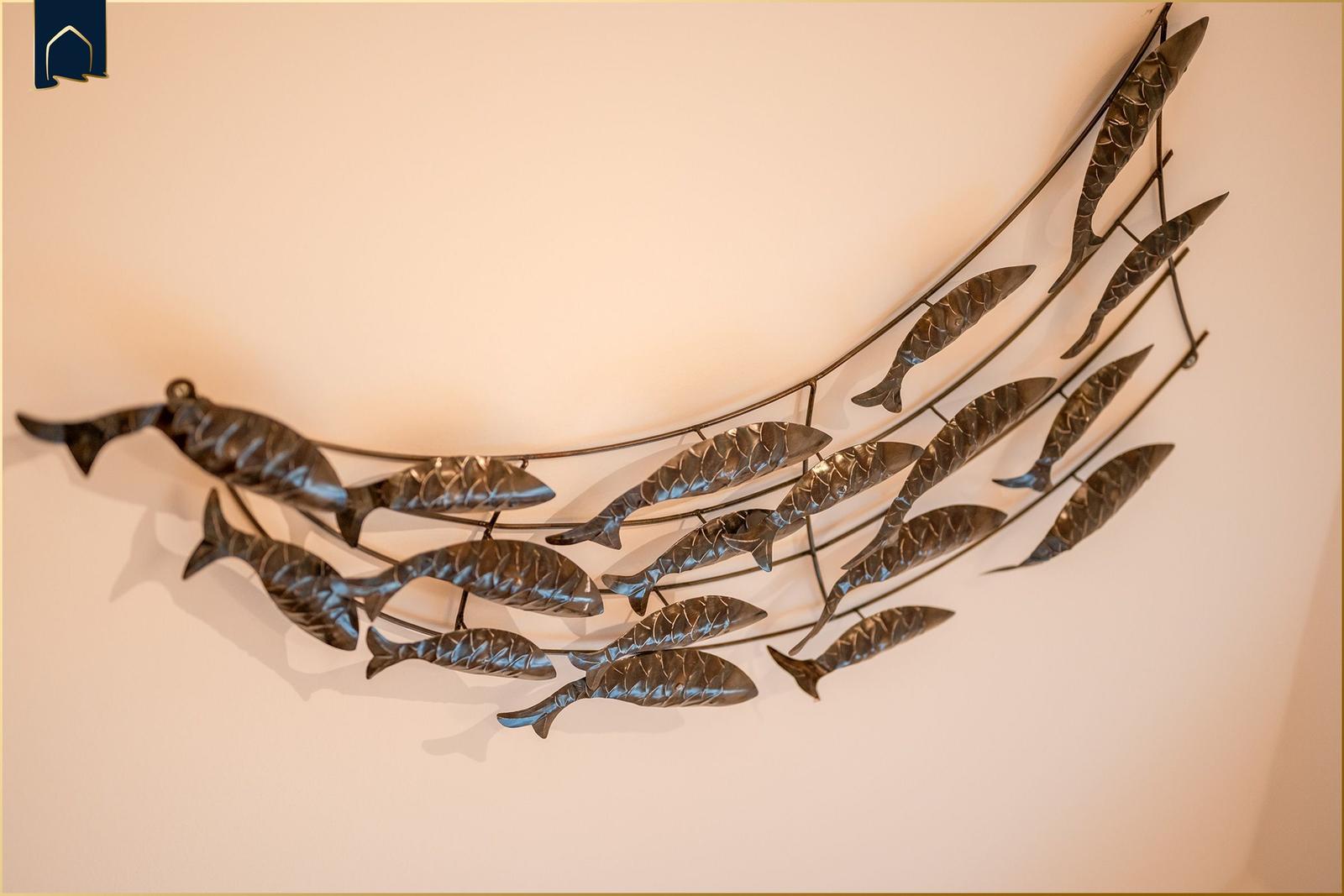 Metallkunstwerk mit Fischmotiven an der Wand