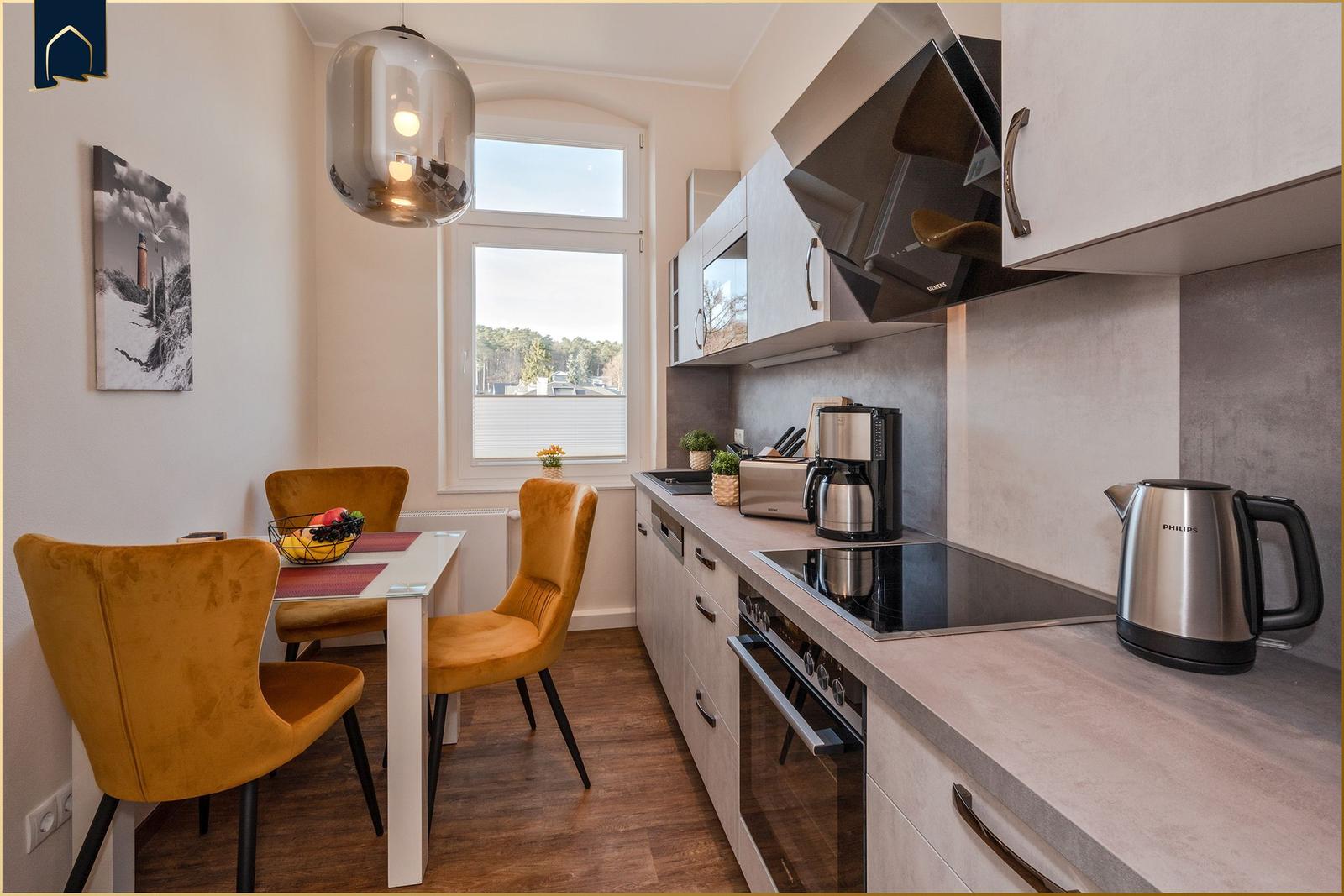 Küche mit Esstisch und Fensterblick. Arbeitsfläche, Kochfeld und Geräte.
