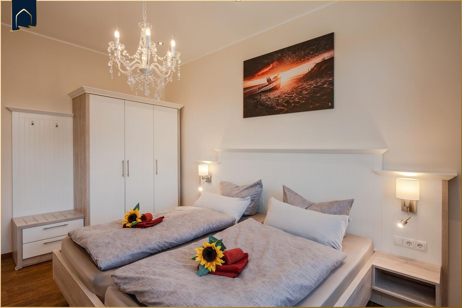 Schlafzimmer mit Doppelbett, Kleiderschrank und Wandbild. Deckenleuchte und Nachttische.