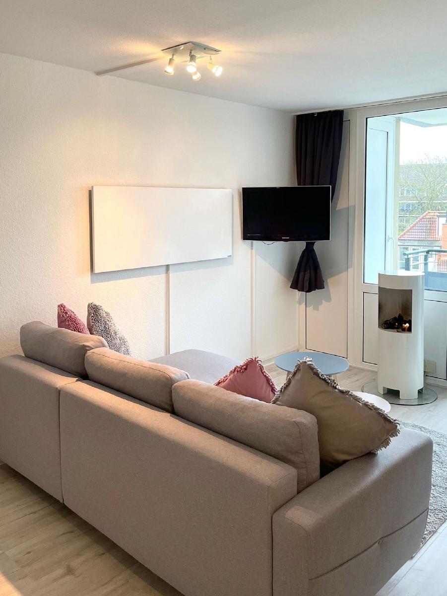 Wohnzimmer mit Sofa, Fernseher und modernem Kamin.