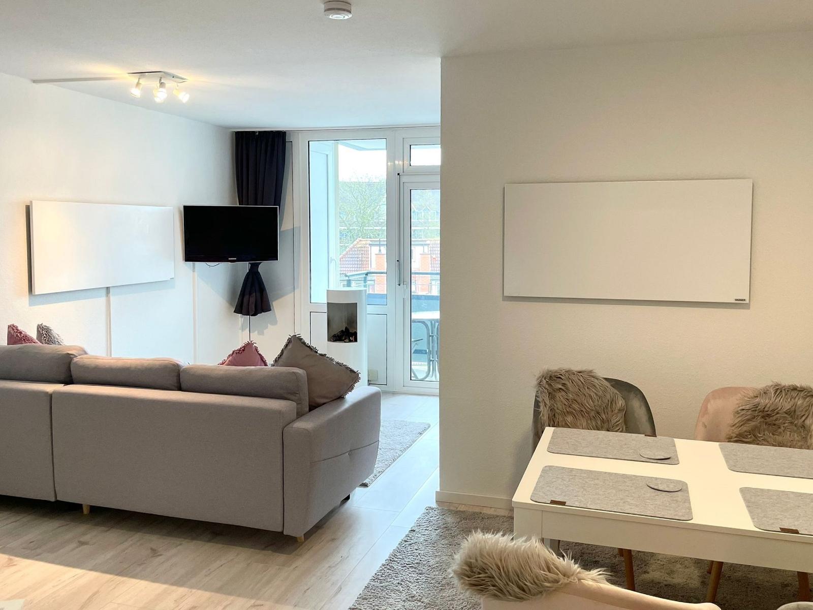 Wohn- und Essbereich mit Sofa, Fernseher und Tisch mit Stühlen.