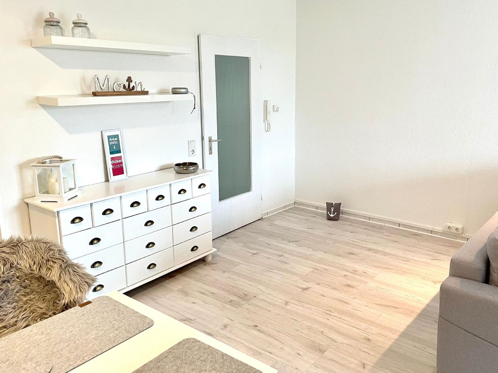 Wohnraum mit weißen Schränken, Holzboden und Tür mit Glas.