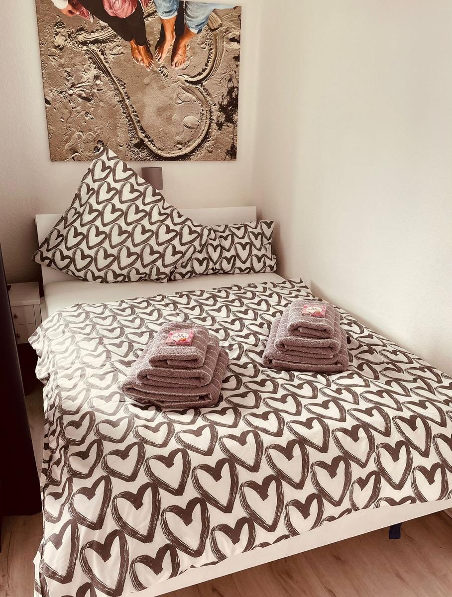Schlafzimmer mit Bett, Herz-Muster-Bettwäsche und Wandbild.