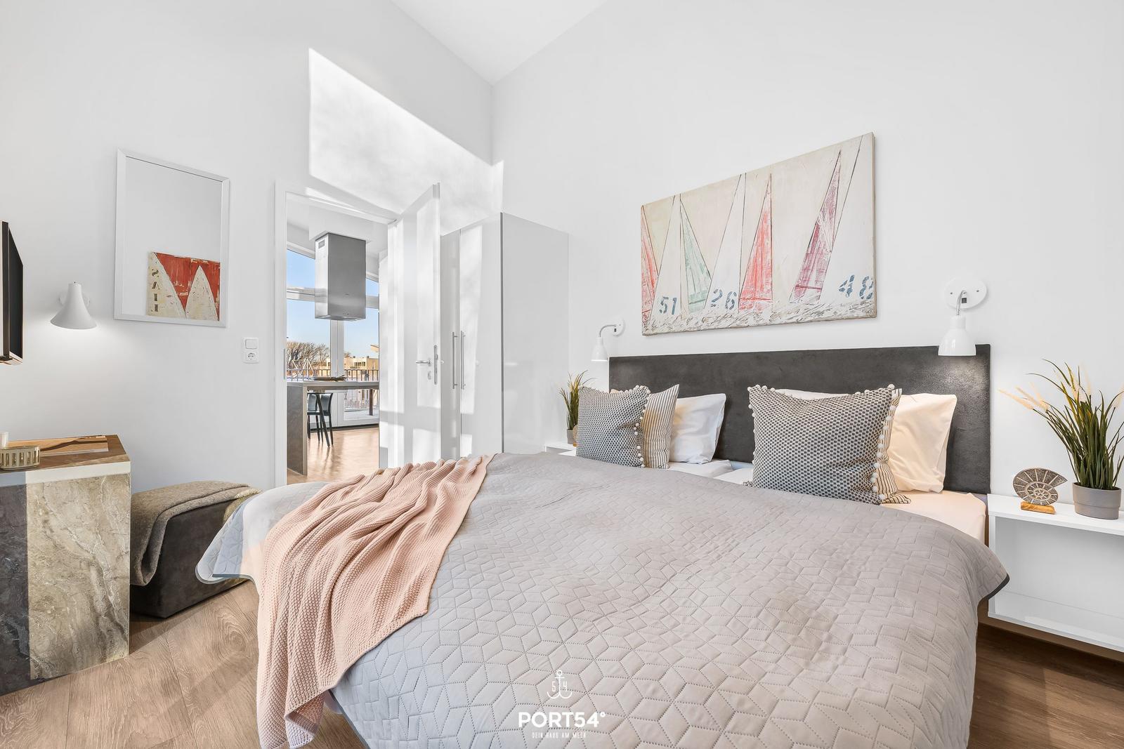 Schlafzimmer mit Bett, Wandbild und Blick auf Balkon.