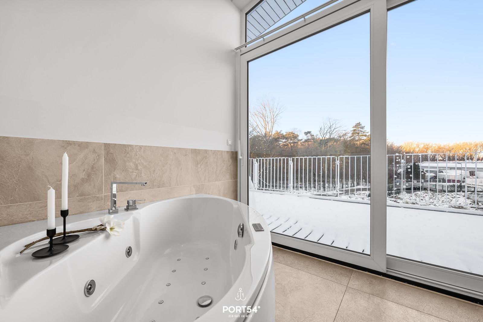 Eine Whirlpool-Badewanne mit Blick auf eine schneebedeckte Terrasse.