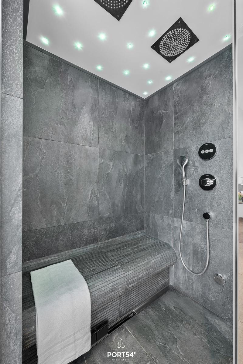 Duschkabine mit Steinwand, Sitzbank und Duschkopf