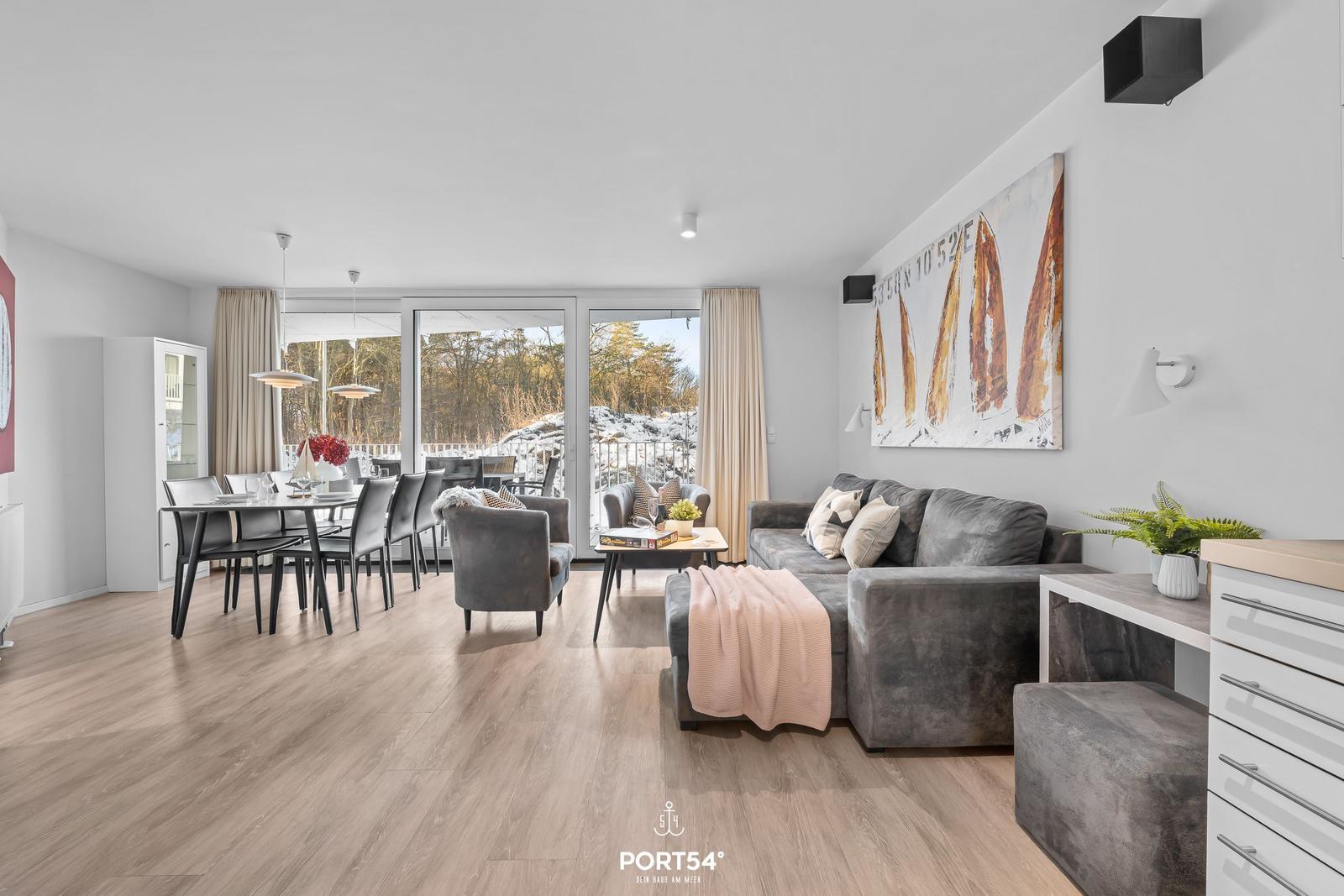 Wohn- und Essbereich mit Sofa, Tisch und Blick auf Balkon