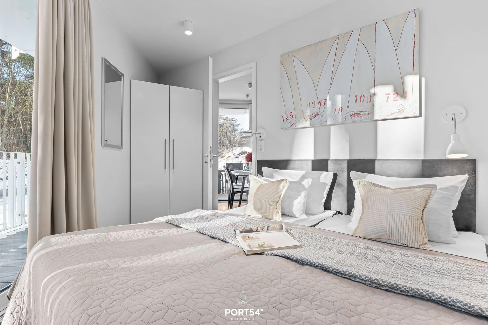 Schlafzimmer mit Bett, Wandbild und Blick auf Balkon.