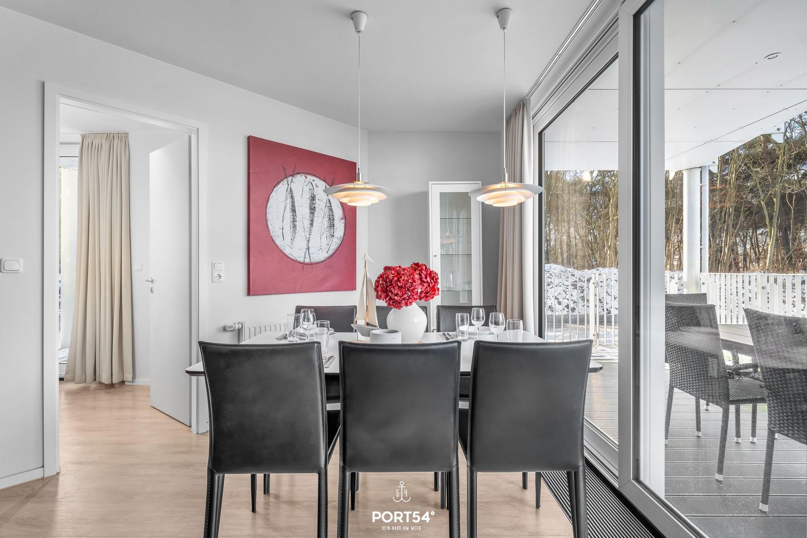 Esszimmer mit Tisch, Stühlen und Blick auf die Terrasse.