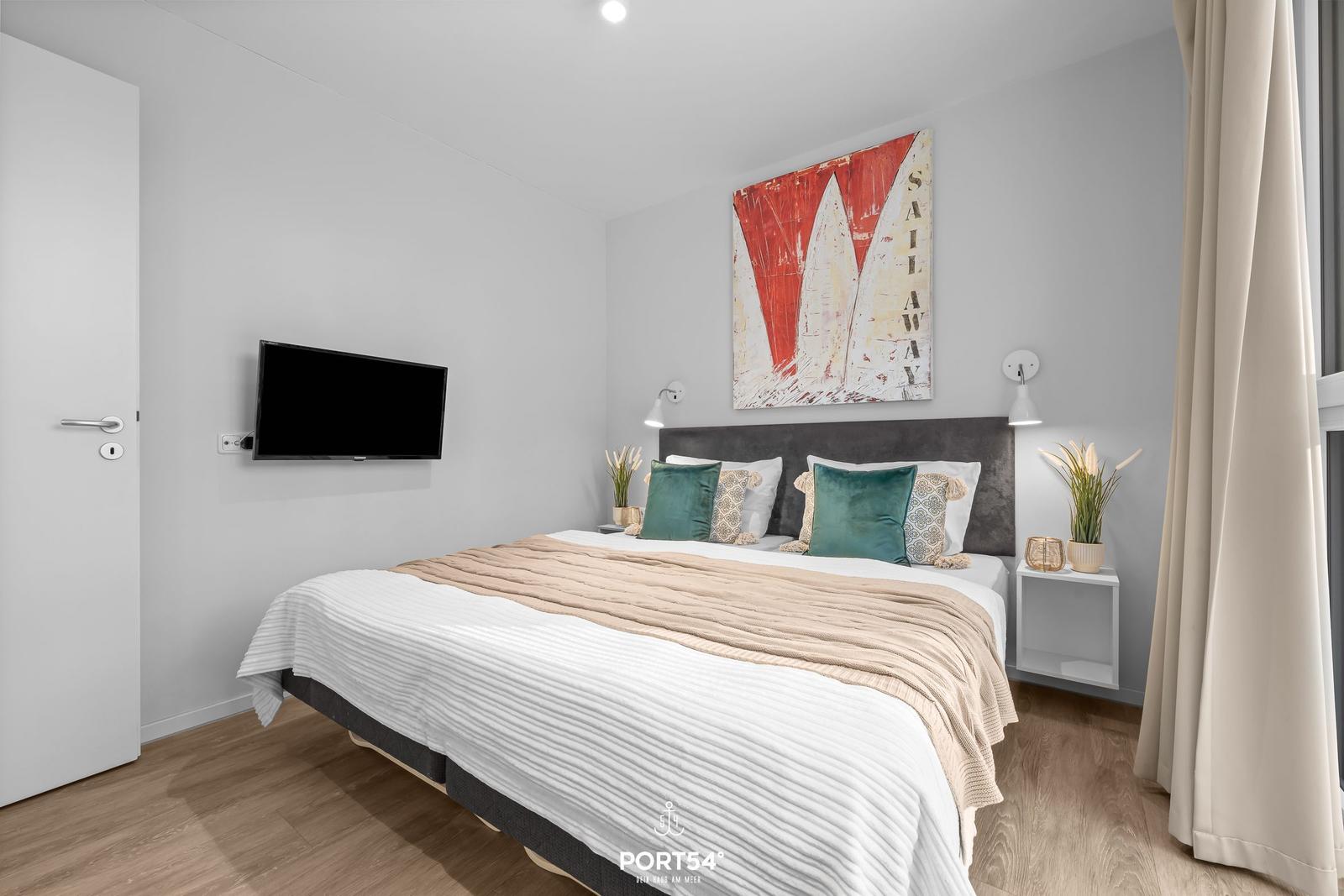 Schlafzimmer mit Bett, Wandbild und Fernseher an der Wand.