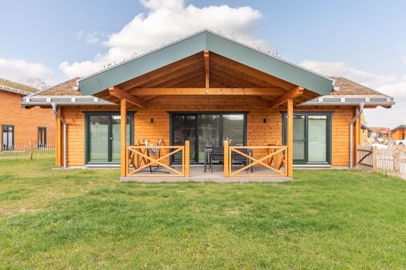 Holzhaus mit überdachtem Balkon, Garten und grünem Dach