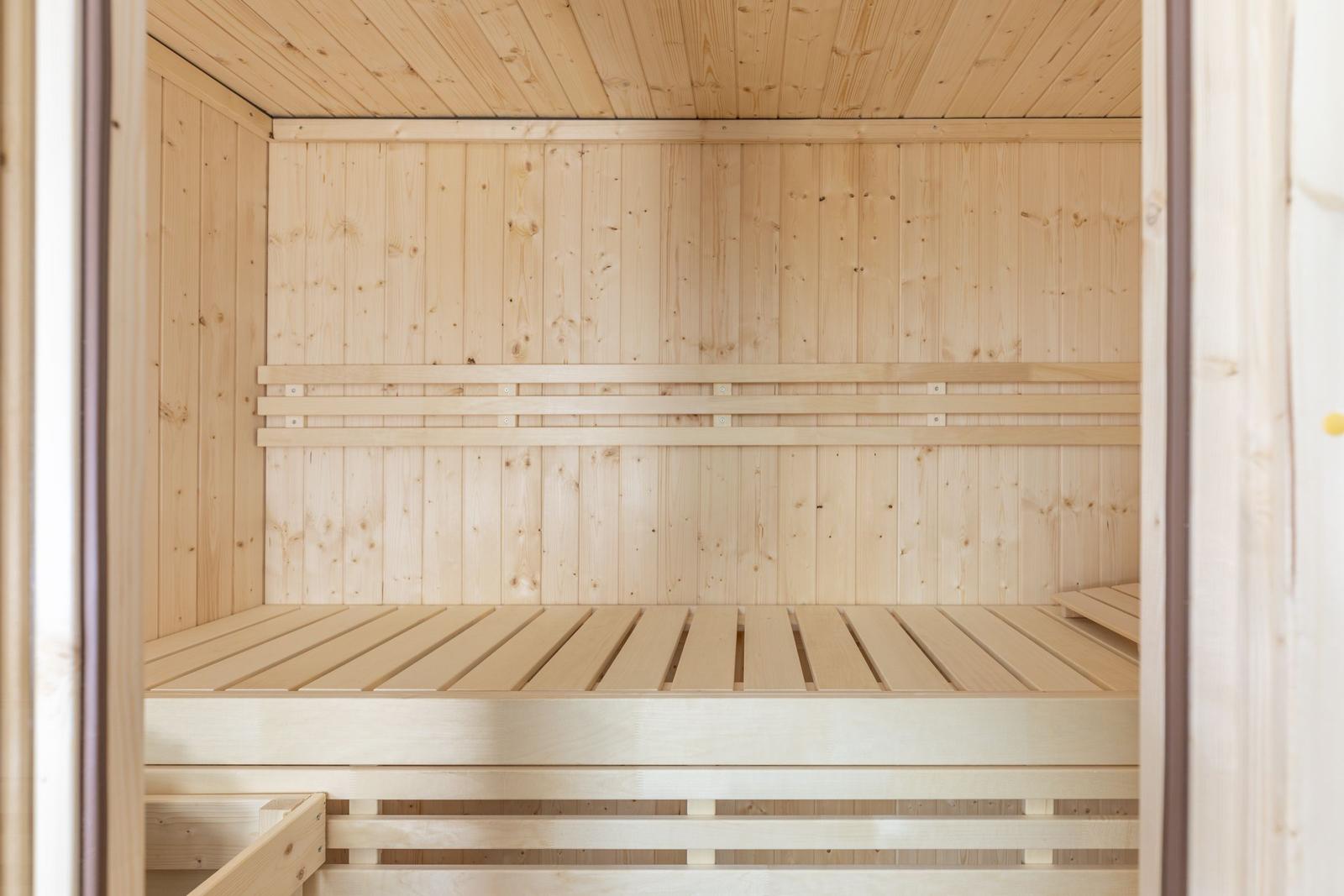 Holzsauna mit mehreren Sitzbänken und einer Holzdecke.