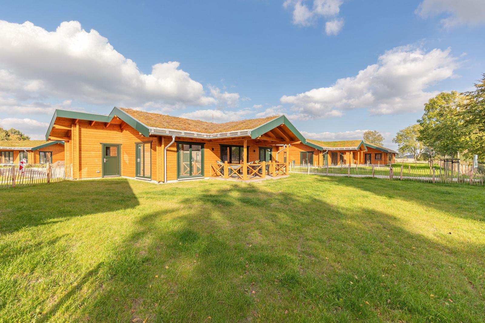 Holzhaus mit Grasdach und Terrasse im Grünen