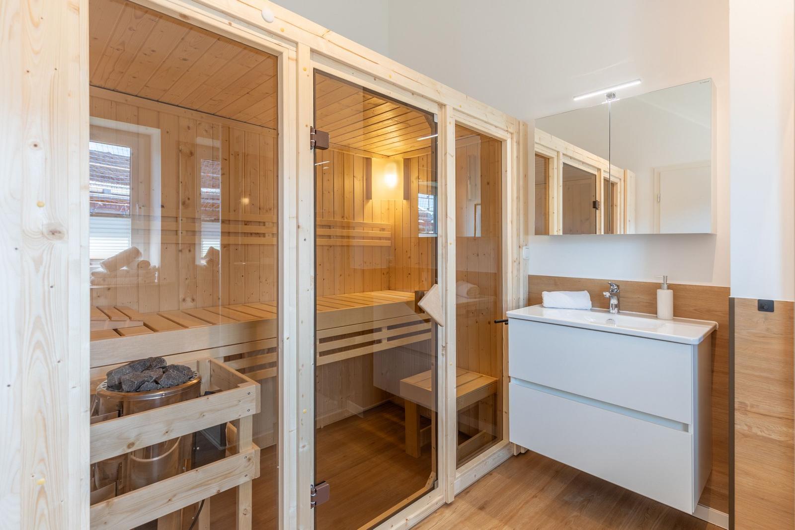 Sauna mit Holzverkleidung und Waschbecken mit Spiegel