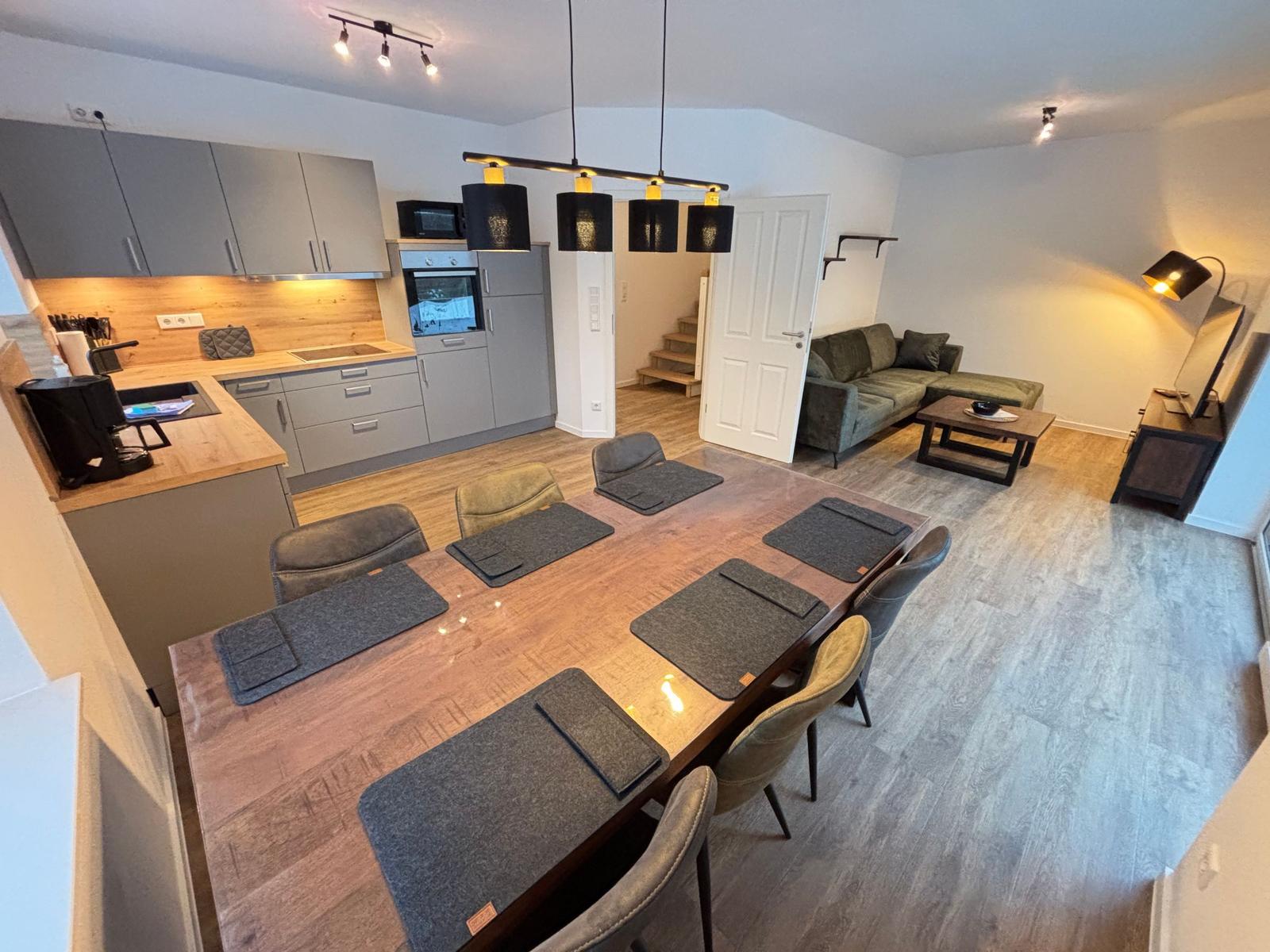 Dining area with table and chairs, kitchen, and living room with sofa and table.