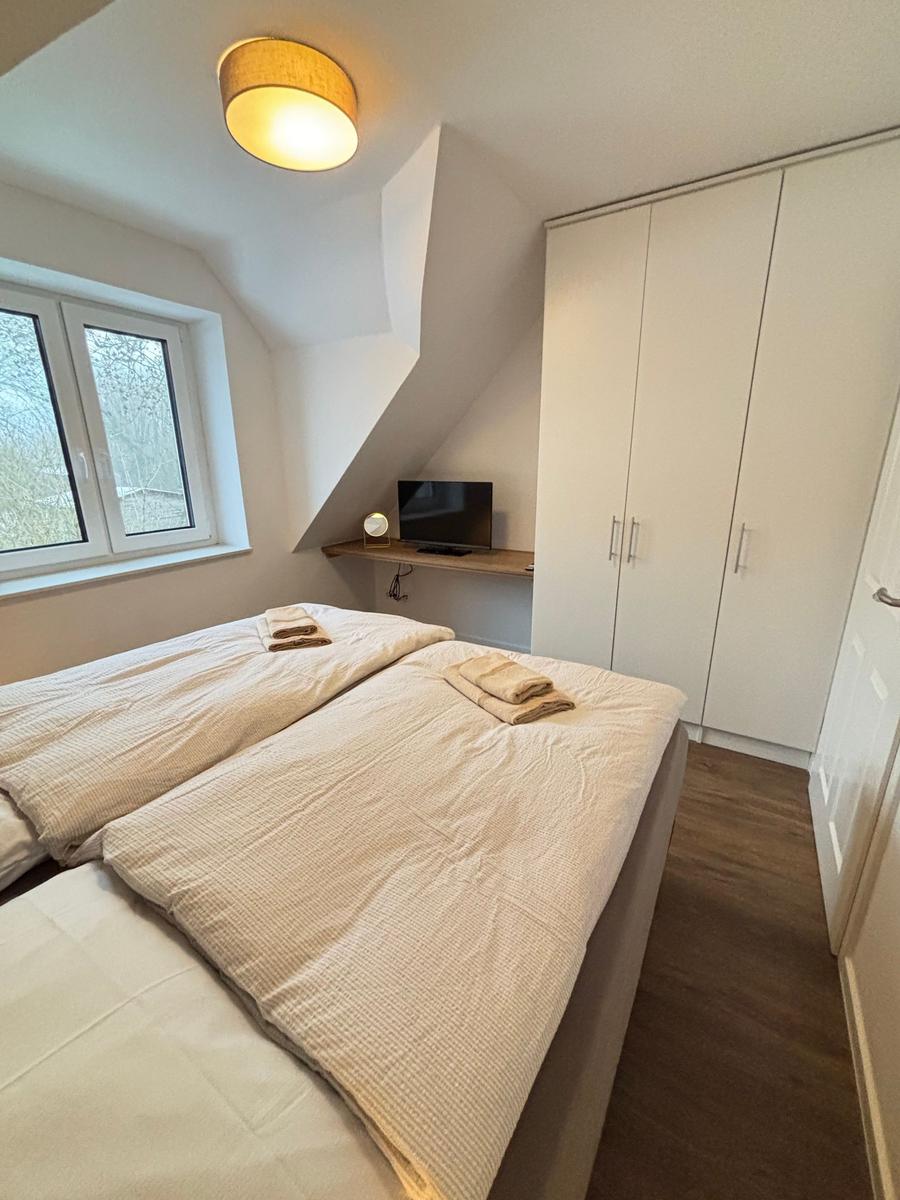 Bedroom with double bed, wardrobe, and window with view of trees.