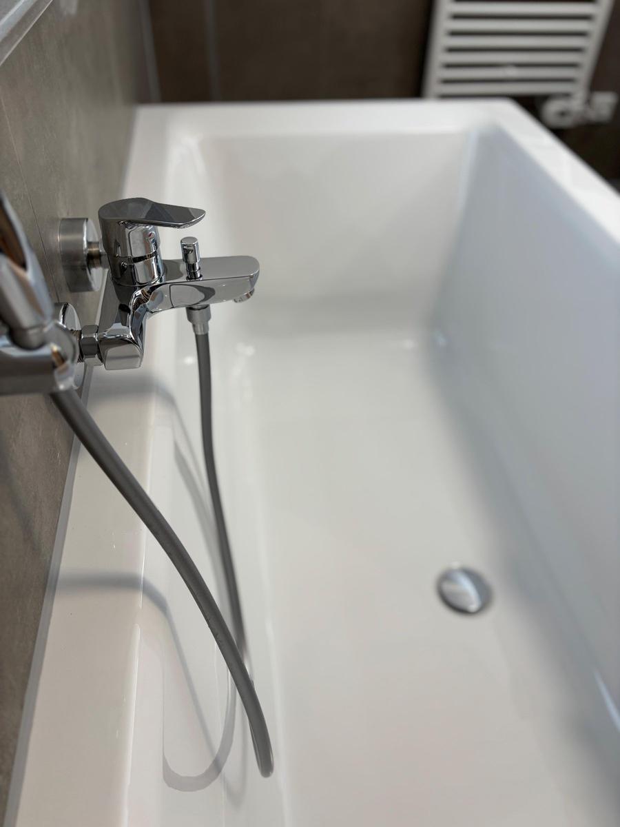 A white bathtub with chrome faucet and handheld shower.