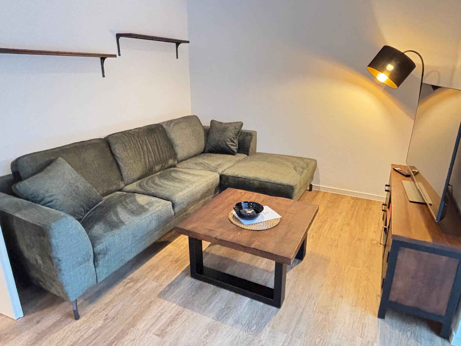 A living room with gray sofa, wooden table, and floor lamp.