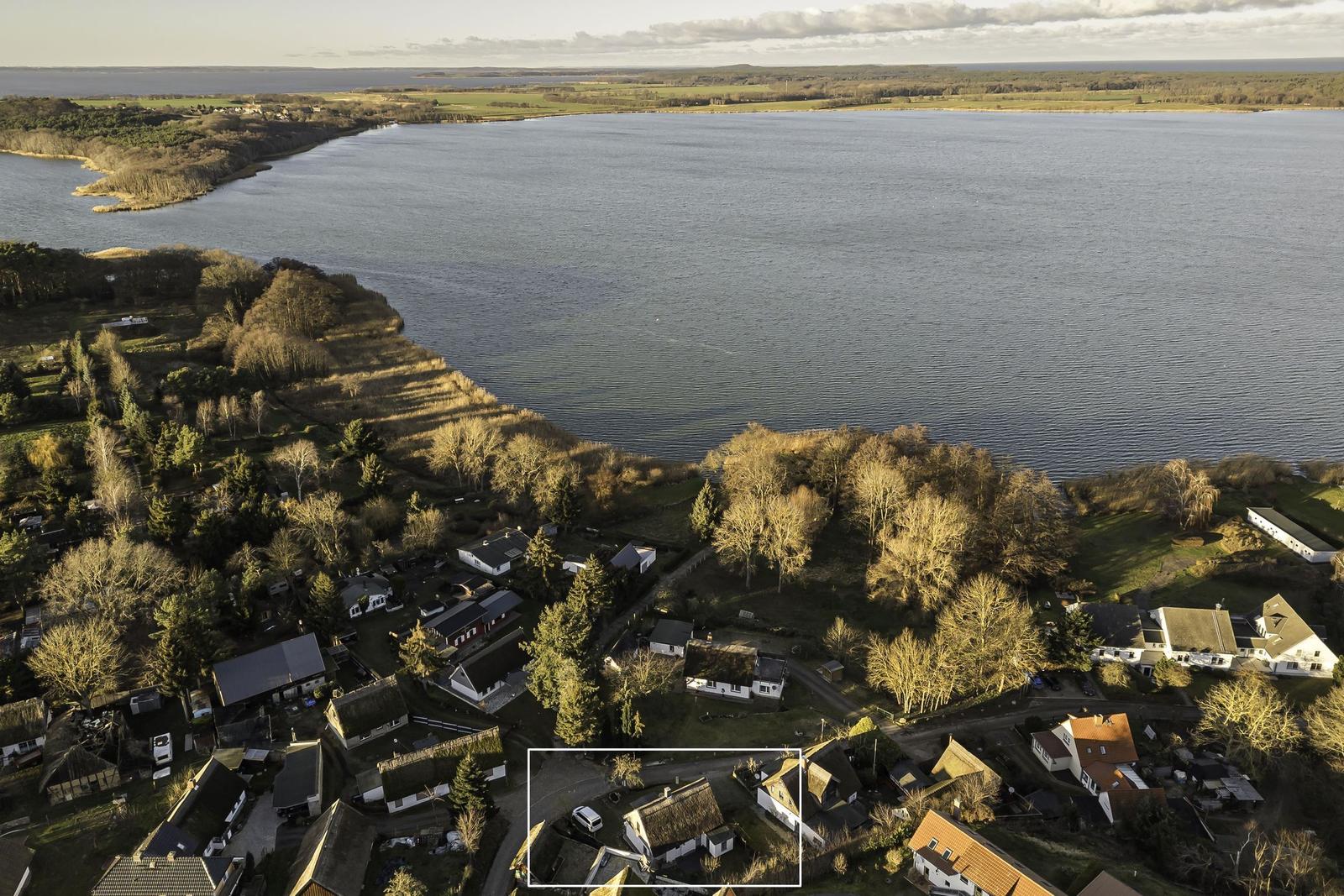 Luftbild eines Dorfes am Wasser mit Häusern und Bäumen.