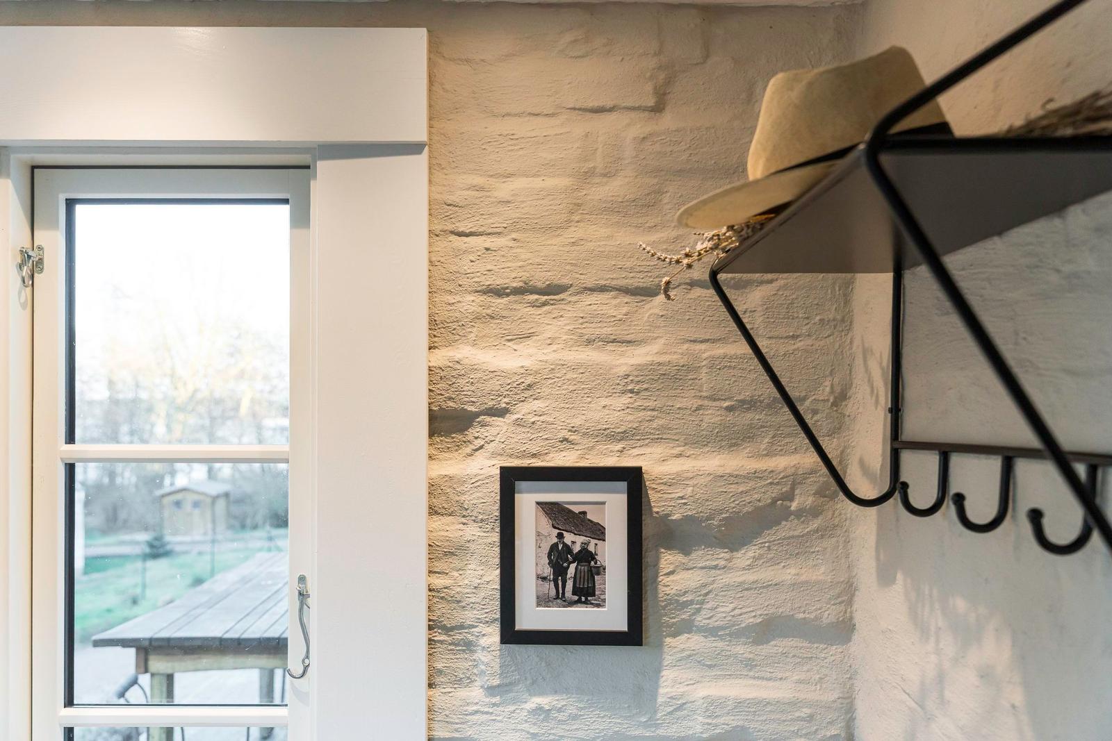 Helle Wand mit Foto, Hutregal und Fensterblick auf Terrasse