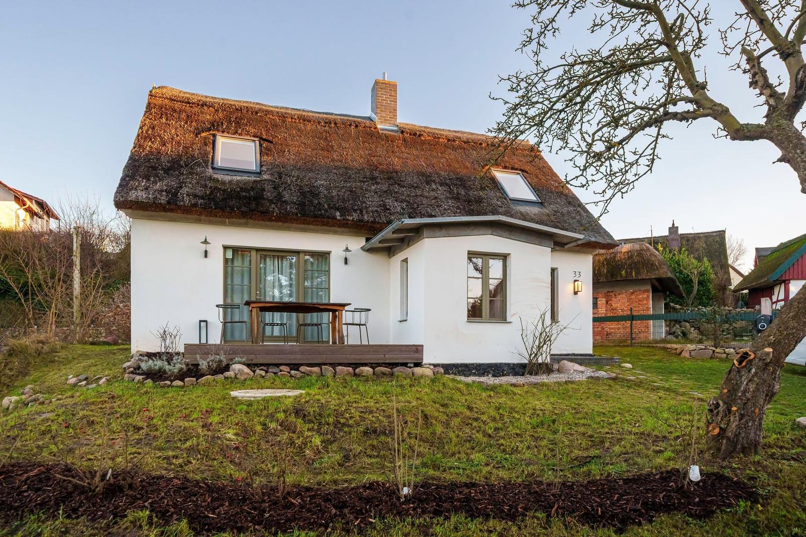 Wohnhaus mit Strohdach, Terrasse und Garten. Hausnummer 33. 