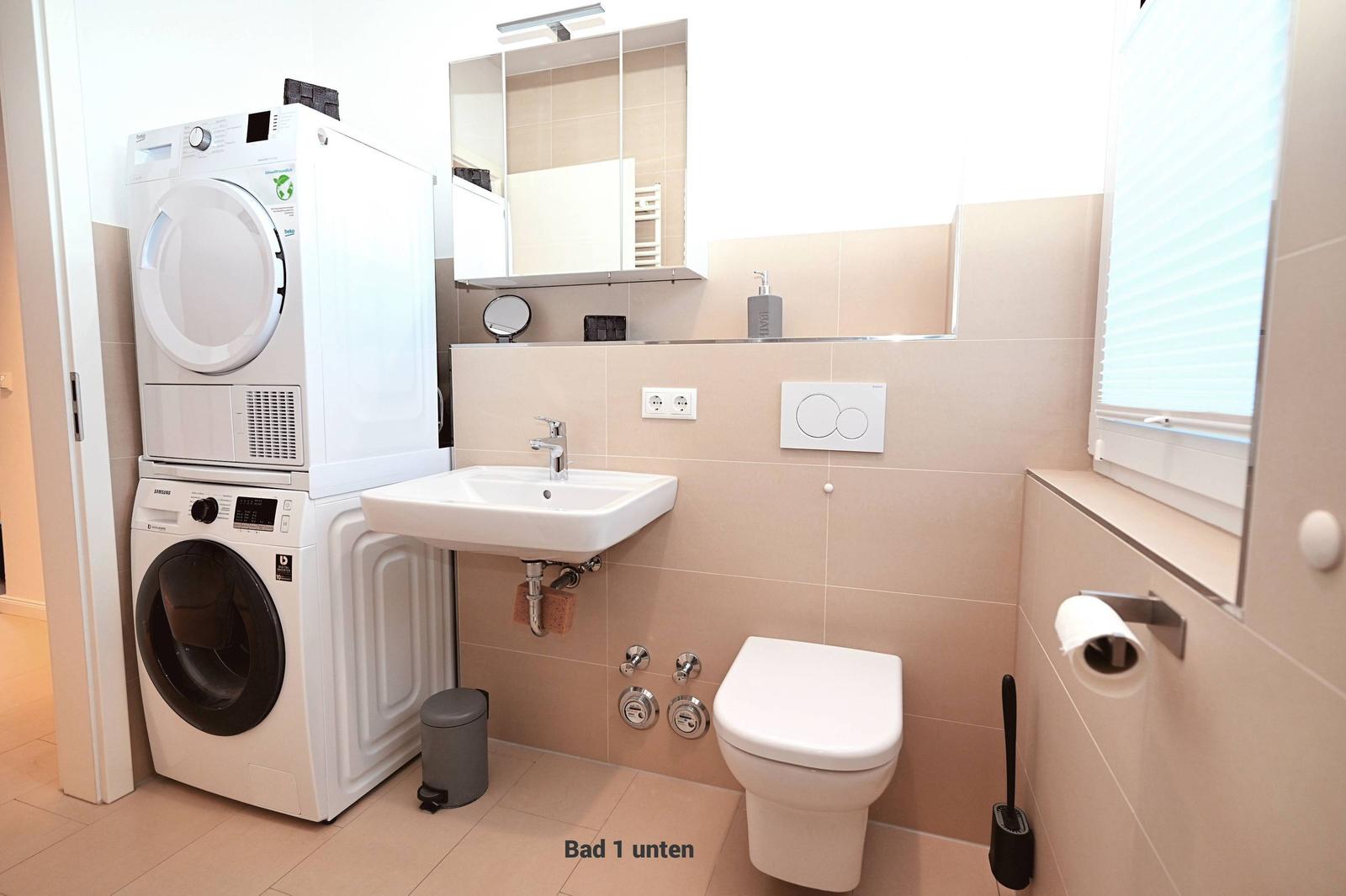 Badezimmer mit Waschmaschine, Trockner, Waschbecken und WC.