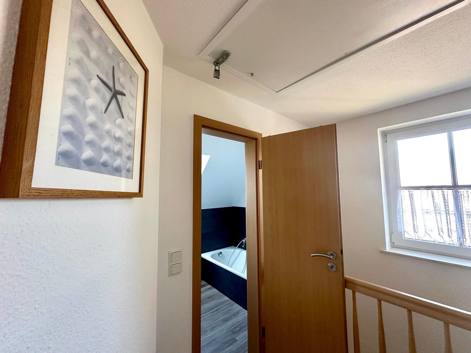 Flur mit Tür zum Bad und Fenster mit Blick auf Balkon