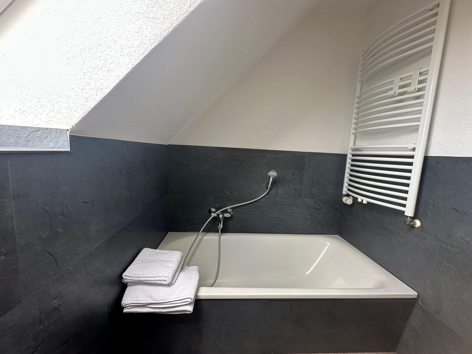 Dusche mit Duschbrause und Handtuchhalter an der Wand