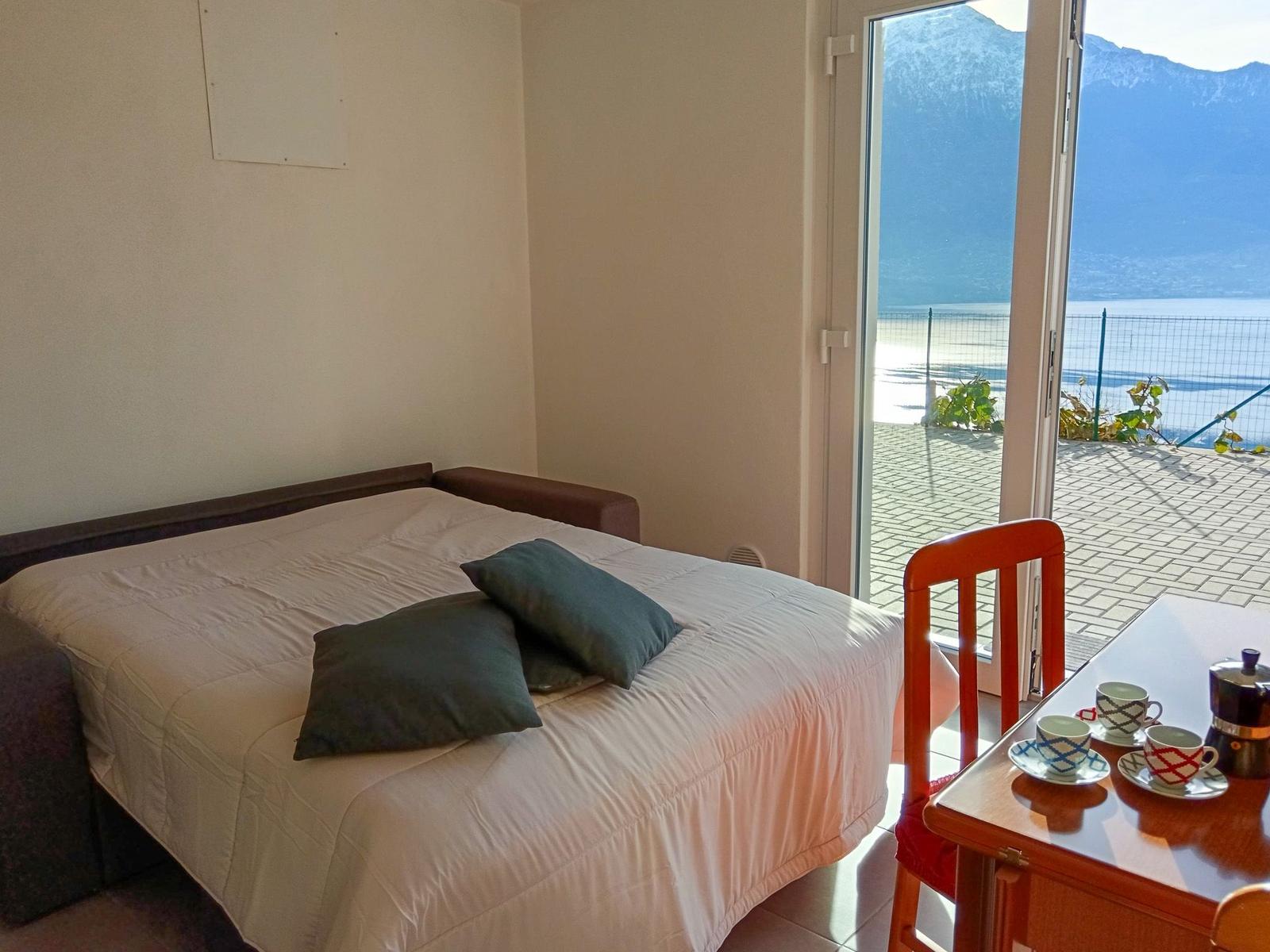 Schlafzimmer mit Blick auf See und Berge. Bett, Tisch und Stuhl sind vorhanden.
