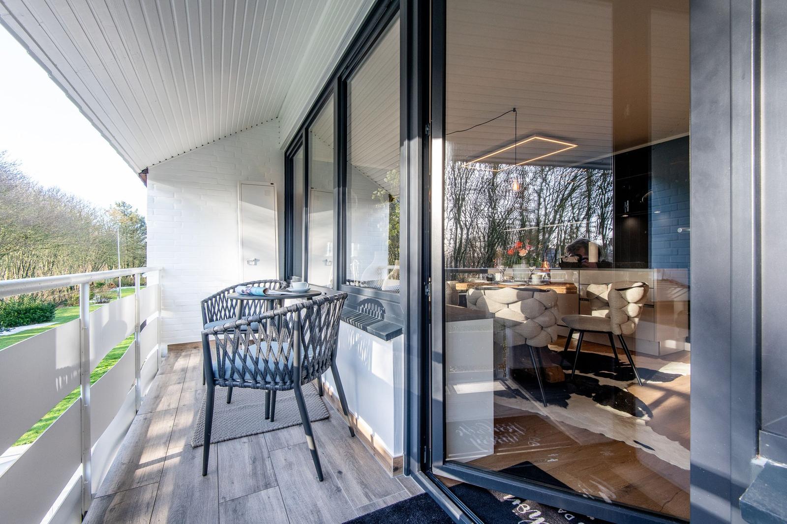 Terrasse mit Tisch und Stühlen, Blick ins Innere mit Essbereich.