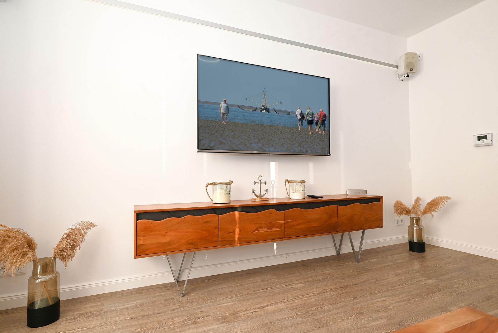 Wohnzimmer mit Fernseher, Holzboard und Dekoration.