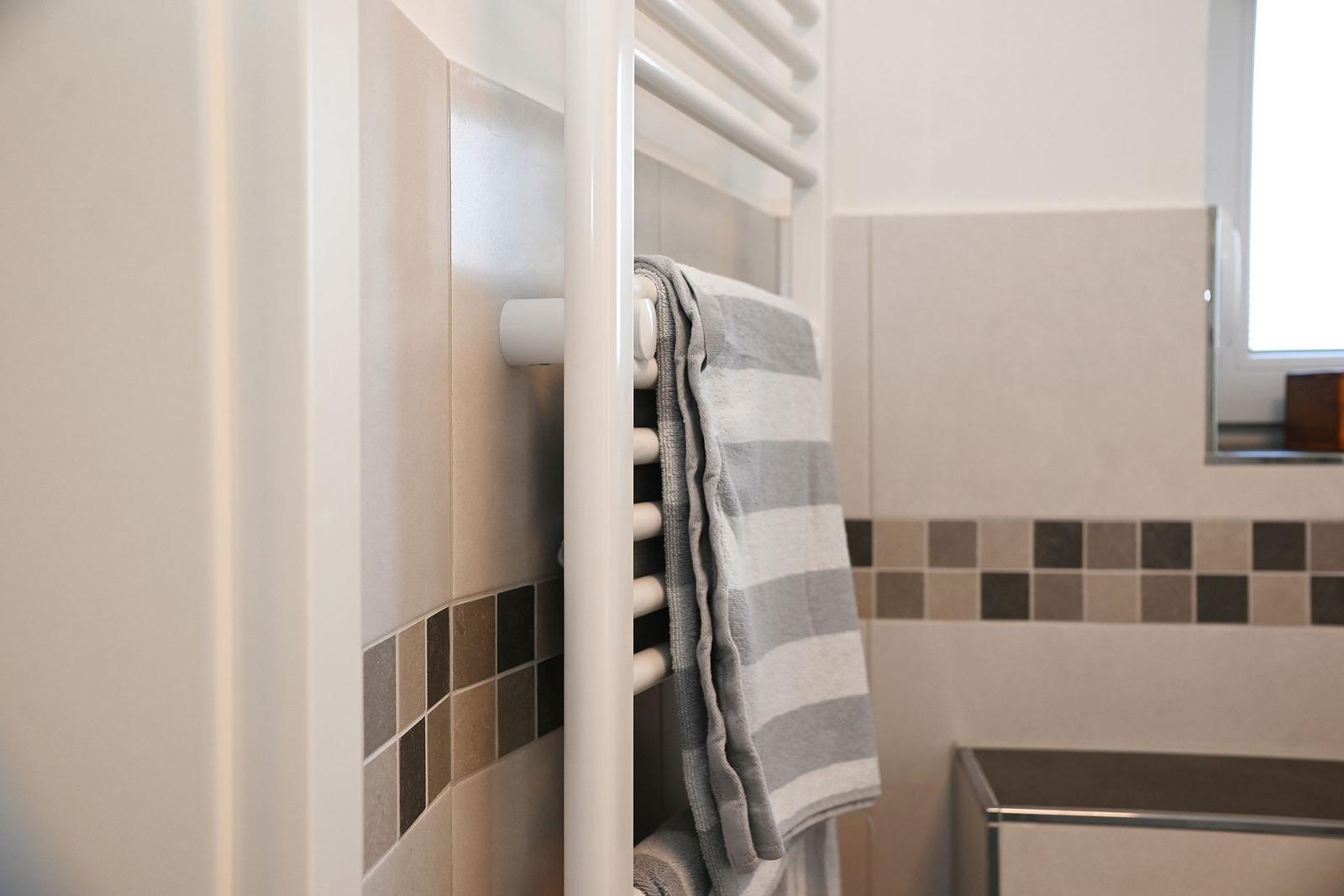 Dusche mit Handtuchhalter und gefliesten Wänden.