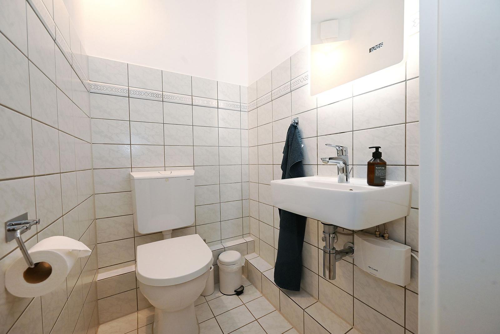 Badezimmer mit Toilette, Waschbecken und Spiegel