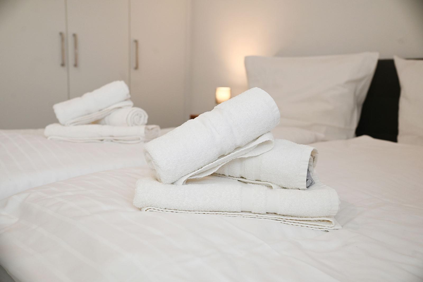 Das Bett ist mit weißen Laken bezogen und mit gefalteten Handtüchern dekoriert.