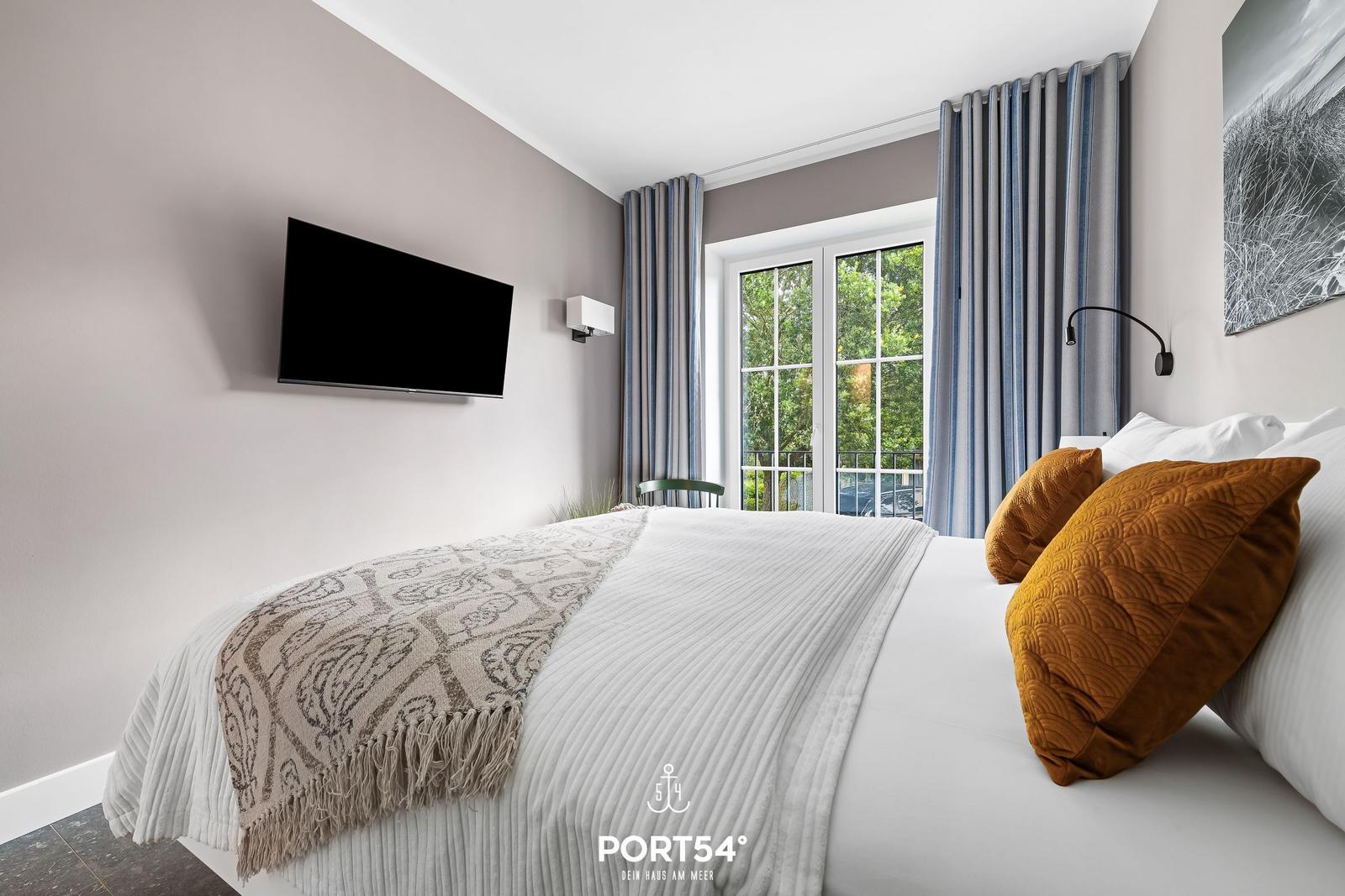 Schlafzimmer mit Bett, TV und Fenster zur Terrasse