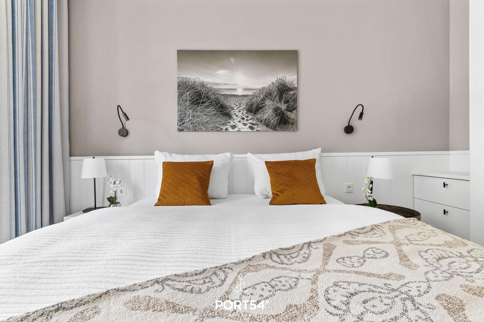 Schlafzimmer mit Bett, Wandbild und Nachttischen.