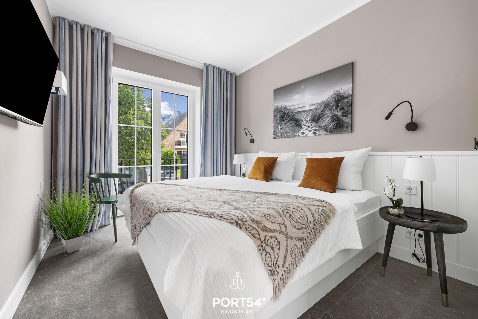 Schlafzimmer mit Bett, Fenster, TV und Nachttisch.
