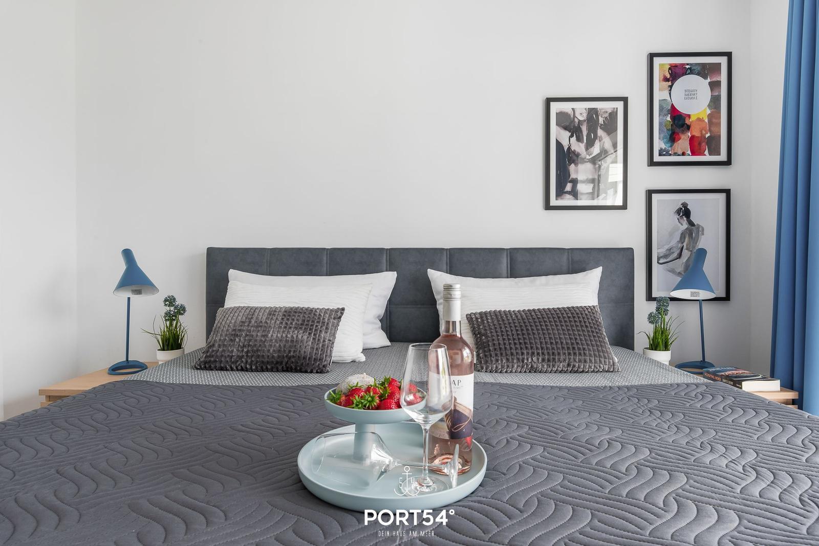 Schlafzimmer mit Bett, Kissen und Bildern an der Wand.