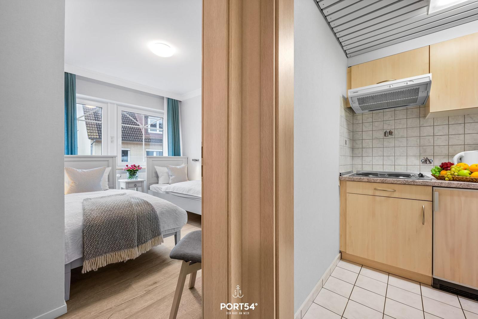 Zwei Schlafzimmer mit Blick auf Dächer. Küche mit Holzschränken und Obst.