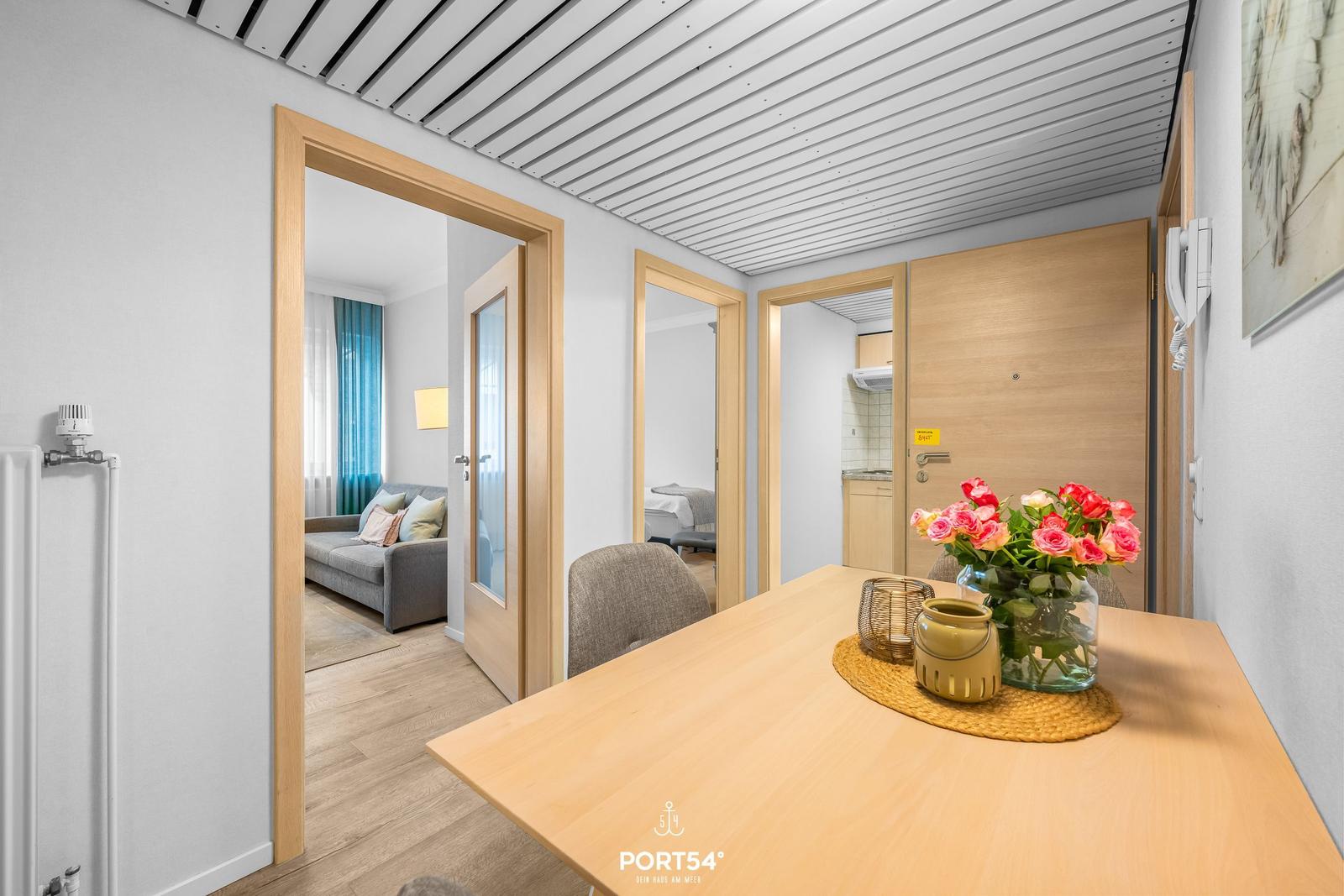 Essbereich mit Tisch und Blumen. Durchgänge zu Wohn- und Schlafzimmer.