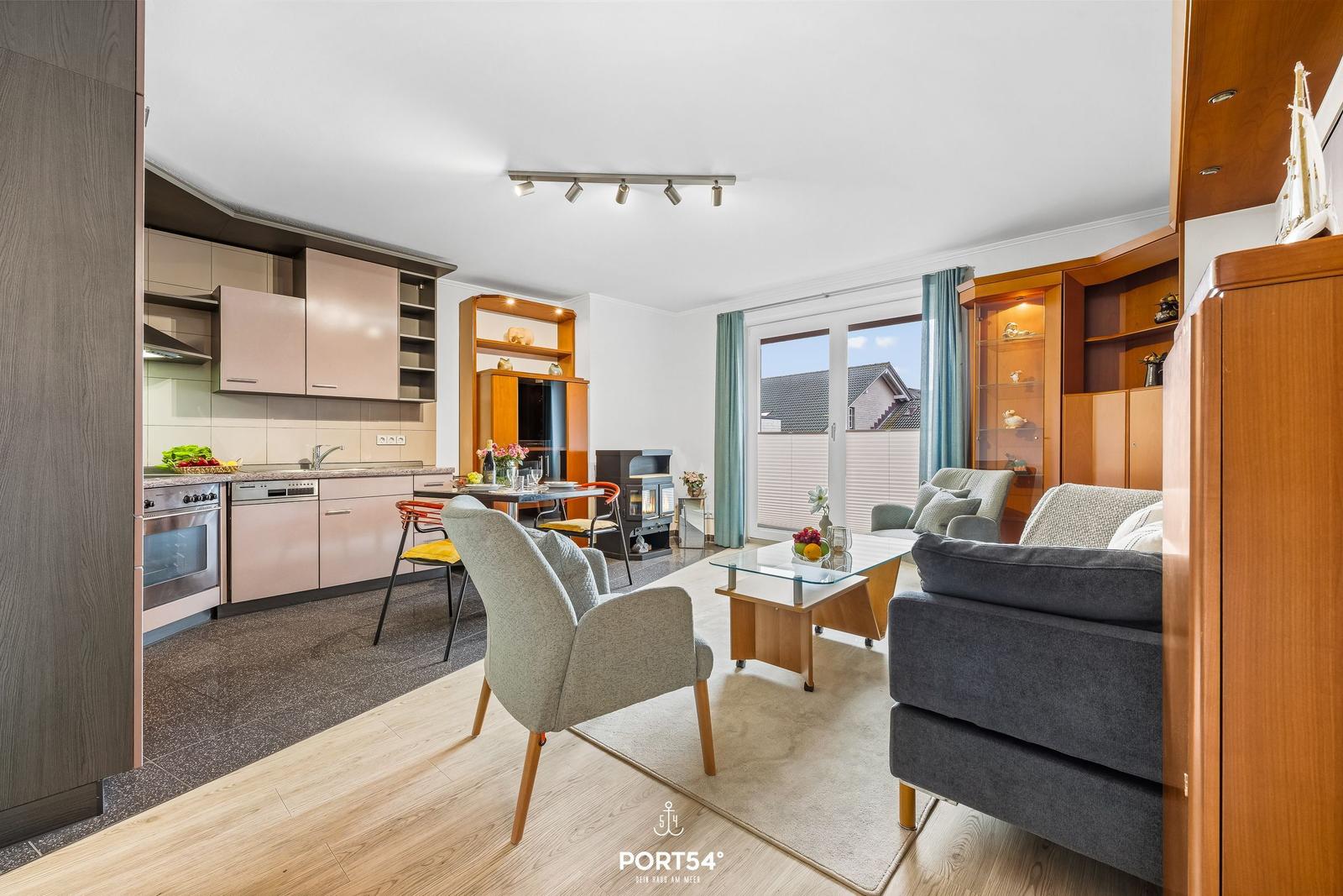 Wohn- und Küchenbereich mit Sitzgelegenheiten und Blick auf Balkon.