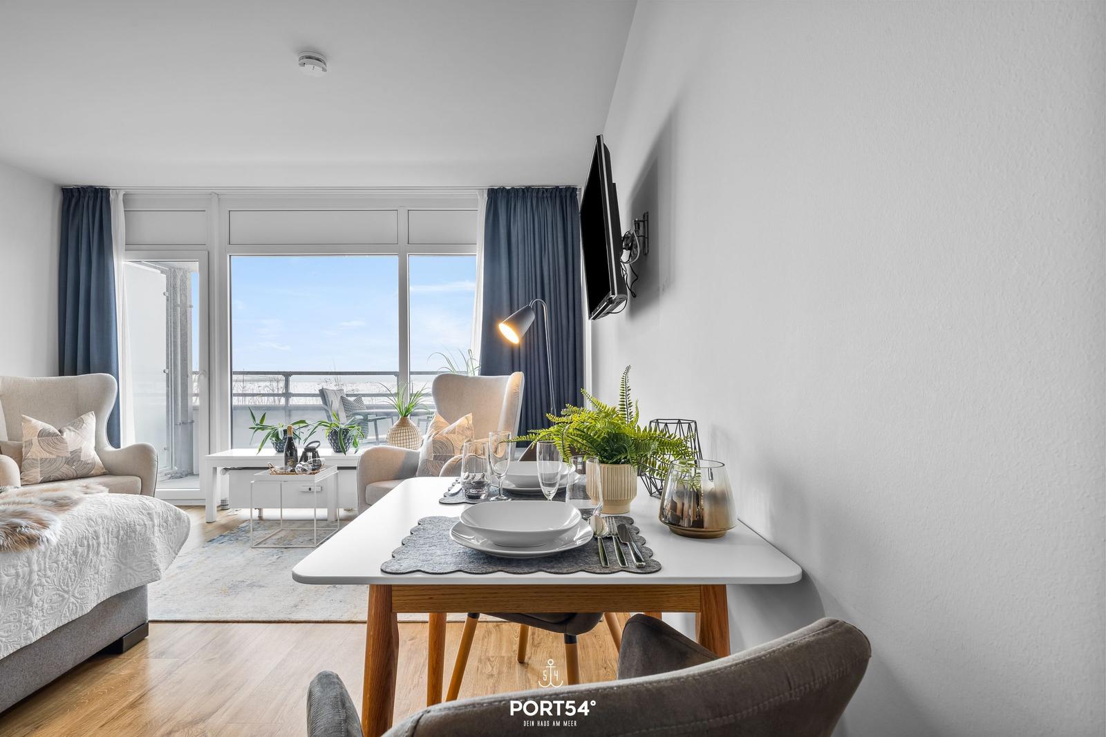 Essbereich mit Tisch und Stühlen, Blick auf Balkon mit Meerblick.